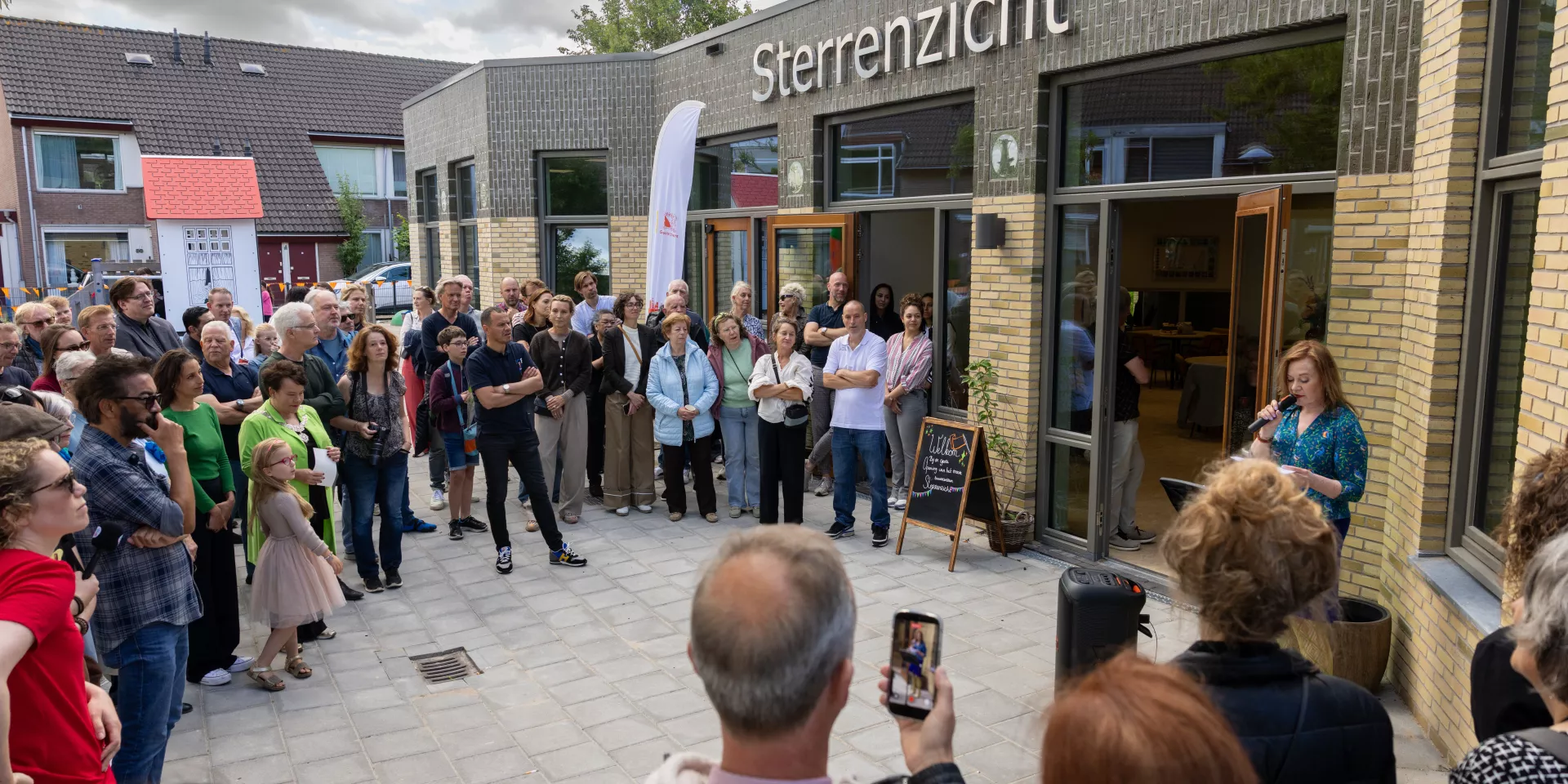 Groep mensen verzameld bij het gebouw met de naam "Sterrenzicht".
